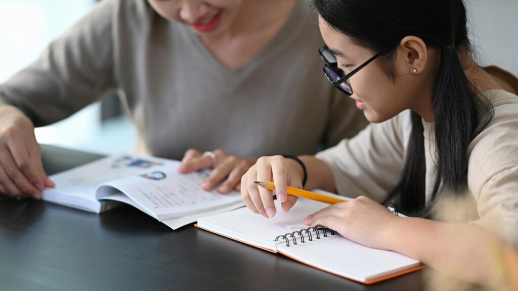 Private tutor helping young student doing homework and lesson practice preparing exam.