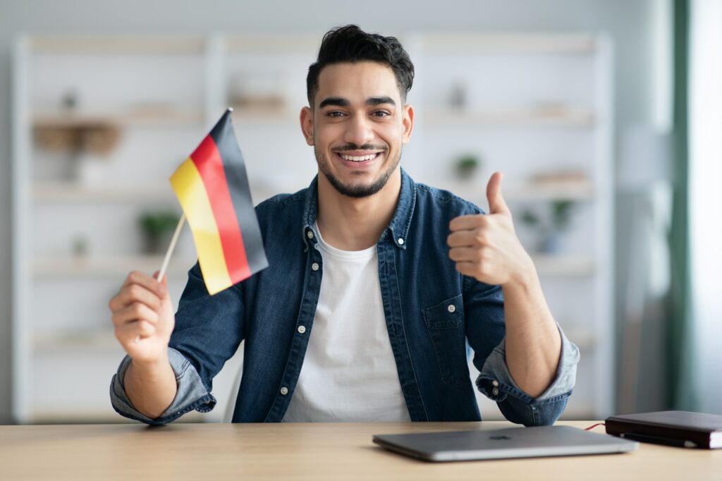 Smiling guy with flag of Germany and showing thumb up